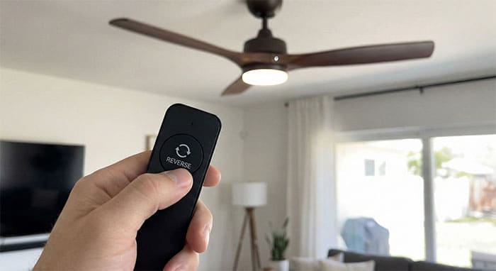 Người dùng đang dùng remote nhấn nút đảo chiều gió cho quạt trần động cơ DC một cách dễ dàng