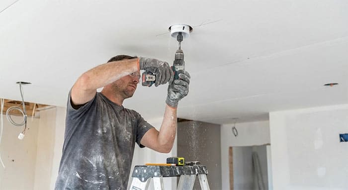 Thợ thi công đang sử dụng mũi khoét chuyên dụng để tạo lỗ trên trần thạch cao cho đèn âm trần