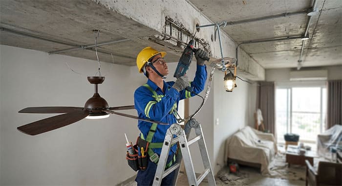 Kỹ sư thực hiện thao tác khoan cấy ty ren gia cố quạt trần lên dầm bê tông cốt thép