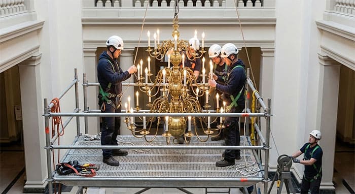 Kỹ thuật viên đang lắp đặt đèn chùm nến thông tầng kích thước lớn