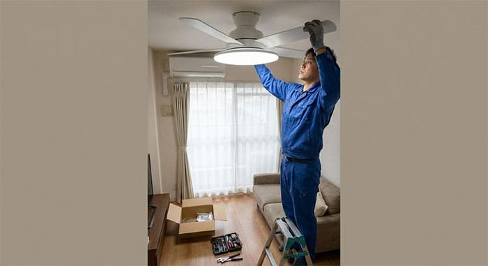 Kỹ thuật viên đang lắp đặt quạt trần sát trần có đèn LED đĩa cho không gian nhà nhỏ