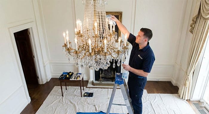 Nhân viên kỹ thuật đang vệ sinh đèn chùm pha lê một cách tỉ mỉ