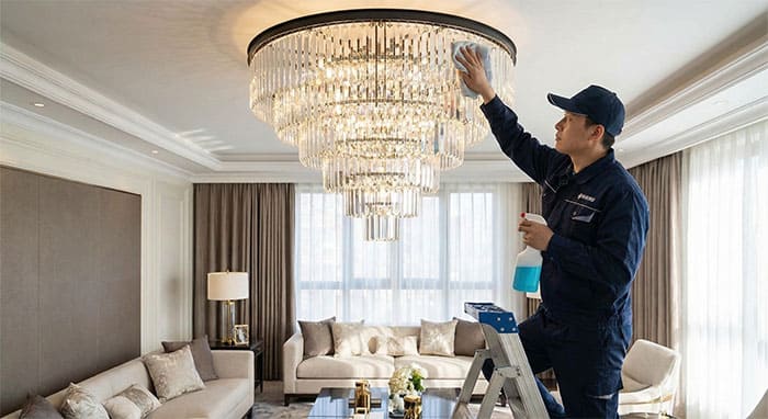 Nhân viên kỹ thuật đang vệ sinh đèn mâm pha lê để đảm bảo độ sáng bóng và hiệu quả phong thủy