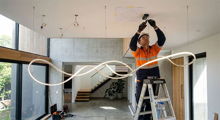 Thợ thi công chuyên nghiệp đang điều chỉnh cáp thả của đèn LED uốn nghệ thuật